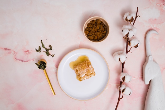 Unicorn statue; coffee grounds; leaves; cotton bud twig with honeycomb on ceramics against pink textured background