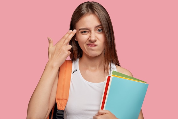 Unimpressed beautiful student posing against the pink wall