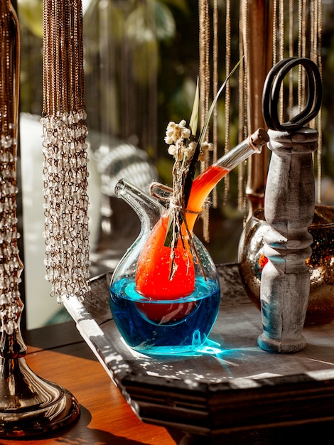 Unique beverage jug with two parts filled with orange and blue cocktails
