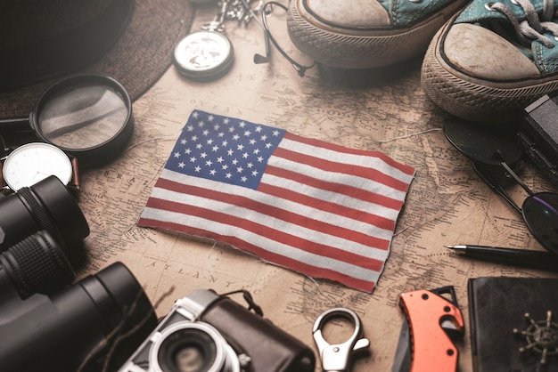 United states of america flag between traveler's accessories on old vintage map. tourist destination concept.