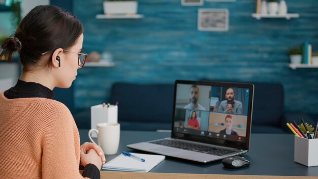 Студент университета посещает встречу по видеосвязи с людьми в онлайн-школе, используя ноутбук дома. Женщина разговаривает на удаленной телеконференции, обучает вебинару в чате.