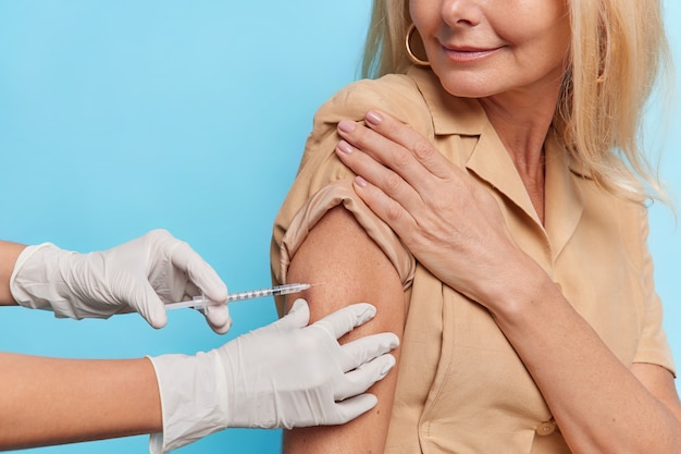 Unknown doctor makes insulin or flu vaccination shot to female patient holds syringe with dose of vaccine