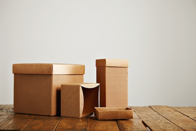 Unlabeled similar boxes of different shapes and sizes on an uneven wooden table isolated on white