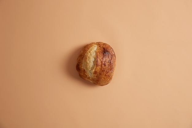 ベージュの背景に分離された、有機天然小麦粉から調製された丸い形の種なしパン。エコライフと有機食品のコンセプト。自家製の焼きたてのパン。ベーカリーのコンセプト