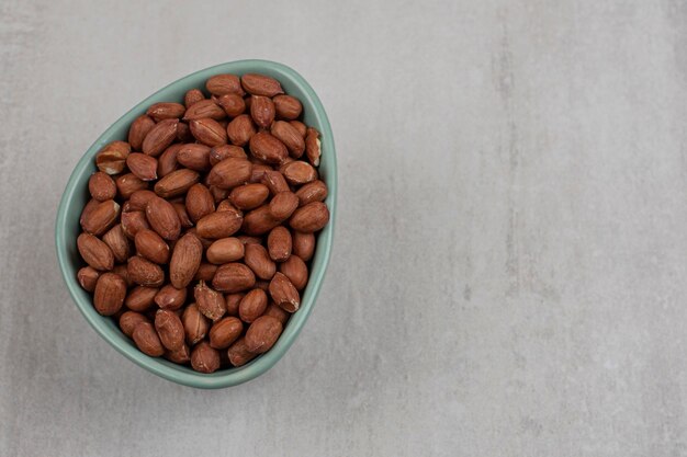 Unpeeled organic peanuts in blue bowl.