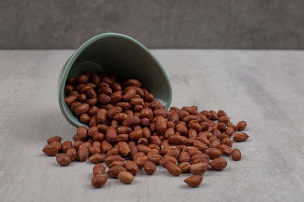 Unpeeled organic peanuts out of blue bowl.