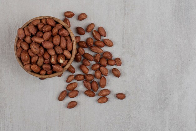 Unpeeled organic peanuts in wooden bowl.