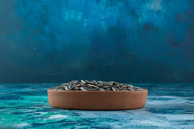 Foto gratuita semi di girasole non pelati in una ciotola di argilla, sul tavolo di marmo.