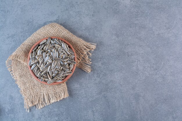 Unpeeled sunflower seeds in clay plate on texture , on the marble surface