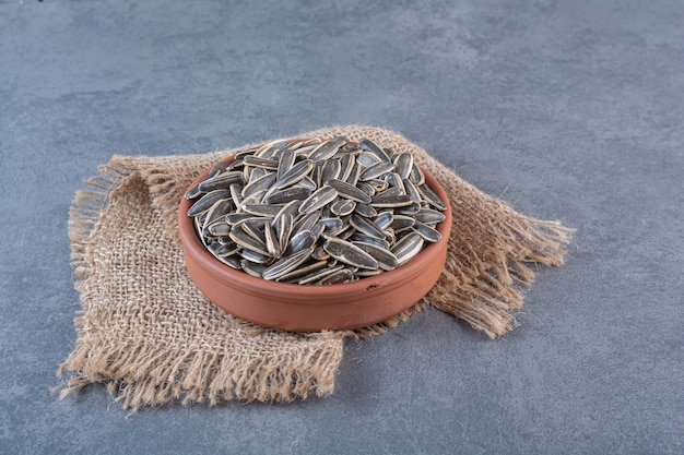 Free photo unpeeled sunflower seeds in clay plate on texture , on the marble surface