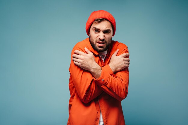 Unpleasant man feeling cold on blue background