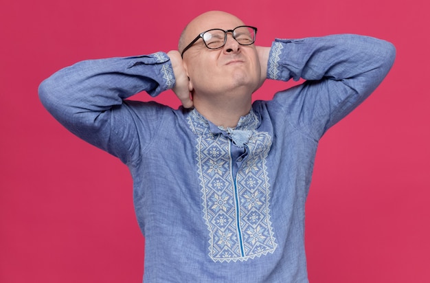 Unpleased adult slavic man in blue shirt wearing optical glasses closing his ears with hands