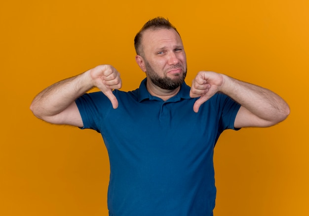 Unpleased adult slavic man looking and showing thumbs down 