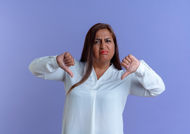 Unpleased casual caucasian middle-aged woman her thumb down isolated on blue wall