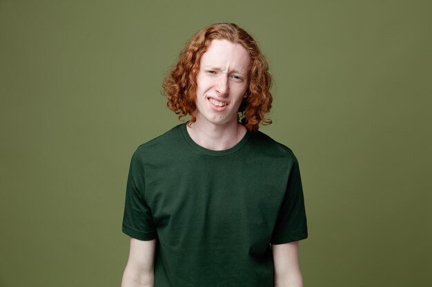 Unpleased looking at camera young handsome guy wearing green t shirt isolated on green background
