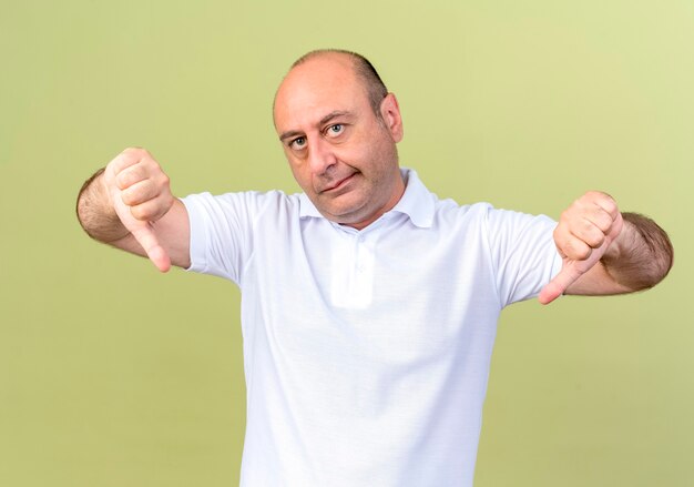 Unpleased mature man his thumbs down isolated on olive green wall