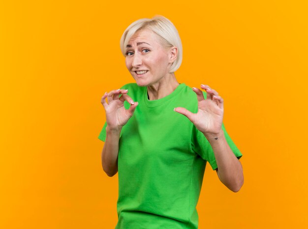 Unpleased middle-aged blonde slavic woman looking at front doing no gesture isolated on yellow wall with copy space