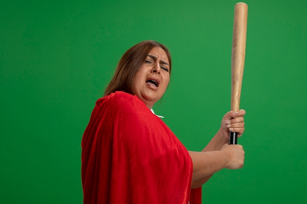 Free photo unpleased middle-aged superhero female raising baseball bat isolated on green background