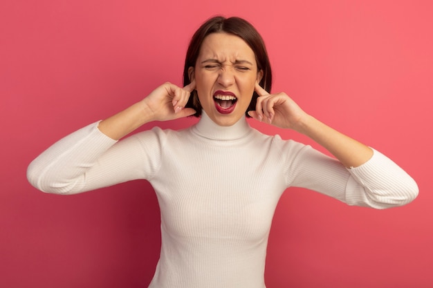 Foto gratuita donna abbastanza caucasica dispiaciuta chiude le orecchie con le dita sul rosa