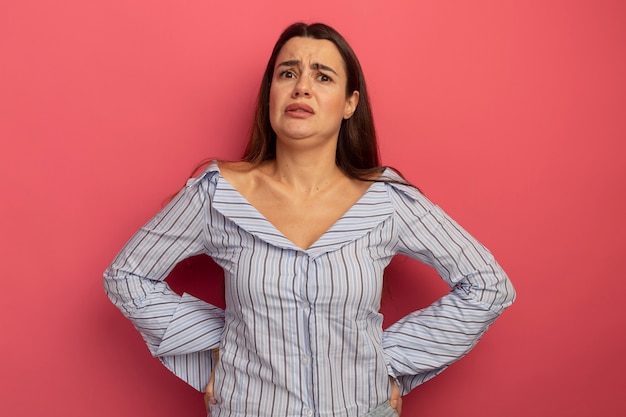 Foto gratuita la donna abbastanza caucasica dispiaciuta tiene le mani dietro la schiena e guarda la telecamera sul rosa