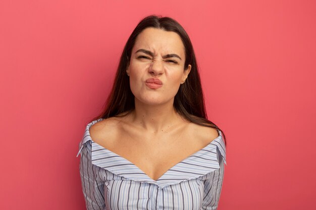 Unpleased pretty caucasian woman looking at camera on pink