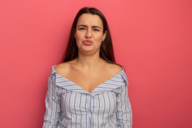 Unpleased pretty caucasian woman looks at camera on pink