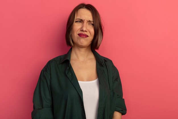 Unpleased pretty woman looking at side isolated on pink wall