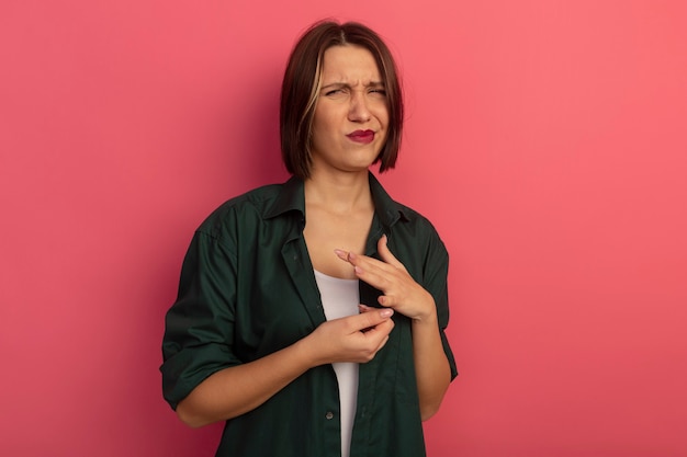 Unpleased pretty woman looks at side isolated on pink wall