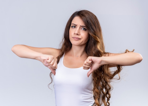 Unpleased young beautiful girl showing thumbs down on isolated white wall