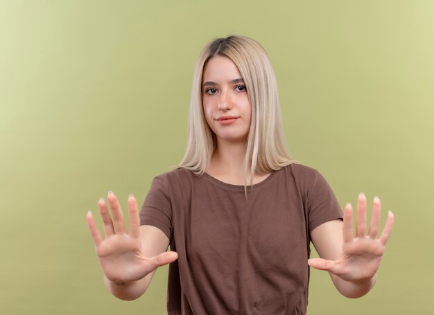 Бесплатное фото Недовольная молодая блондинка не делает жест на изолированной зеленой стене