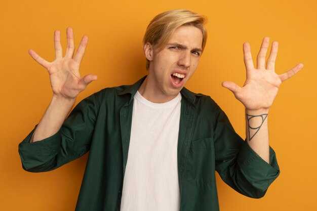Unpleased young blonde guy wearing green t-shirt raising hands