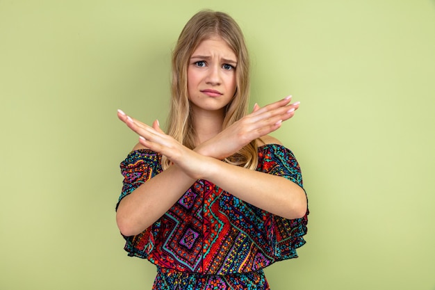 Free photo unpleased young blonde slavic girl crossing her hands gesturing no sign