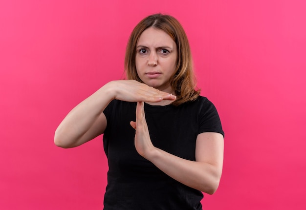 Unpleased young casual woman gesturing timeout on isolated pink wall with copy space