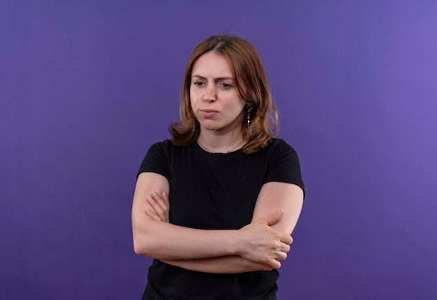 コピースペースと孤立した紫色の壁に閉じた姿勢で立っている不機嫌な若いカジュアルな女性
