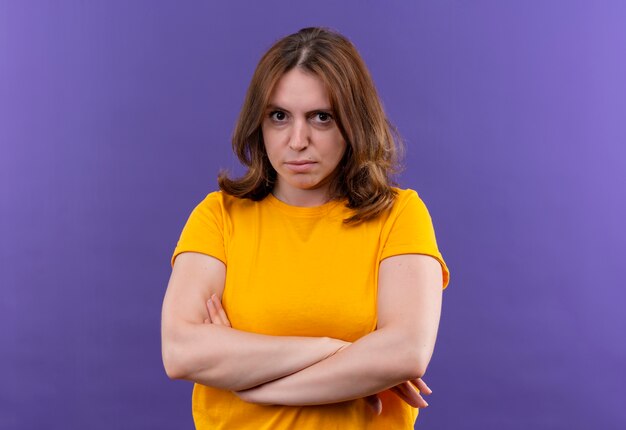 コピースペースと孤立した紫色の壁に閉じた姿勢で立っている不機嫌な若いカジュアルな女性