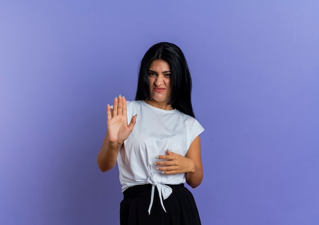 Unpleased young caucasian woman gestures stop hand sign