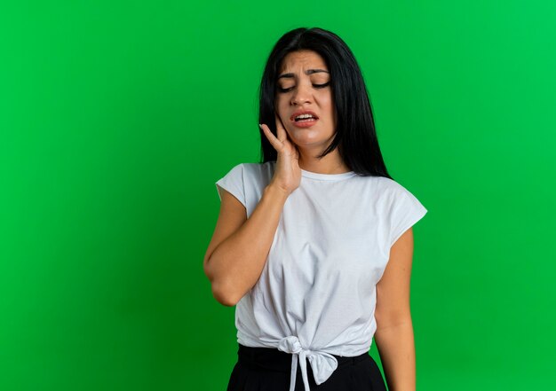 Unpleased young caucasian woman puts hand on face looking down