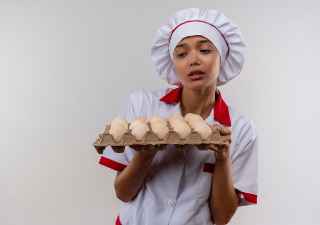 Недовольная молодая женщина-повар в униформе шеф-повара смотрит на партию яиц с копией пространства