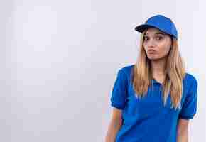 Free photo unpleased young delivery girl wearing blue uniform and cap isolated on white wall with copy space