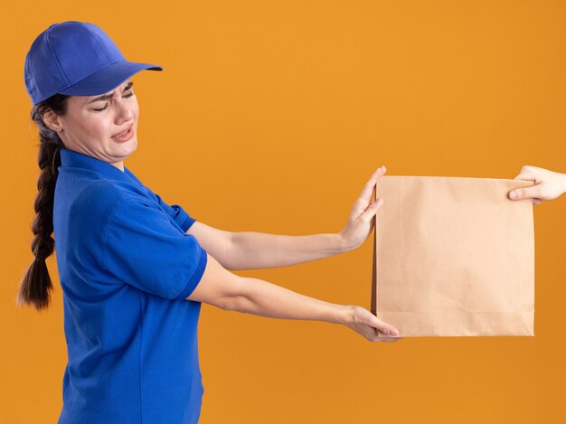 Unpleased young delivery woman in uniform and cap 