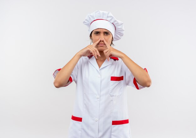 Unpleased young female cook wearing chef uniform closed nose with copy space