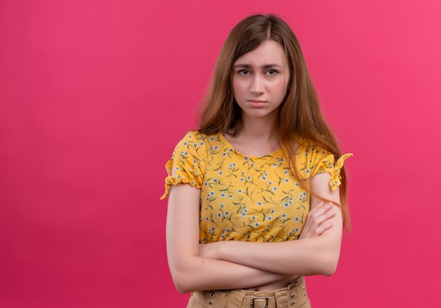 Unpleased young girl standing with closed posture on isolated pink wall with copy space