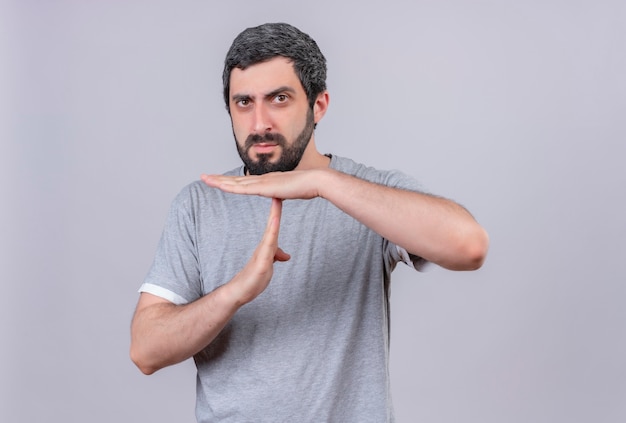 Unpleased young handsome caucasian man doing timeout gesture isolated on white background