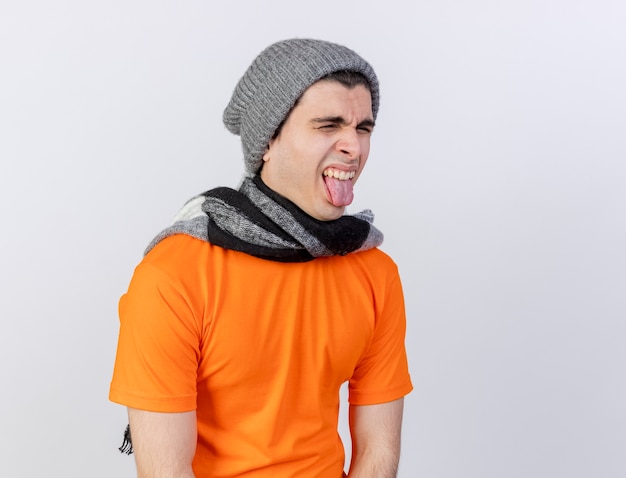 복사 공간 흰색 절연 혀를 보여주는 스카프로 겨울 모자를 쓰고 불쾌한 젊은 아픈 남자