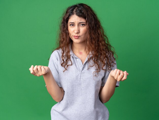 Unpleased young pretty caucasian girl pursing lips doing money gesture 