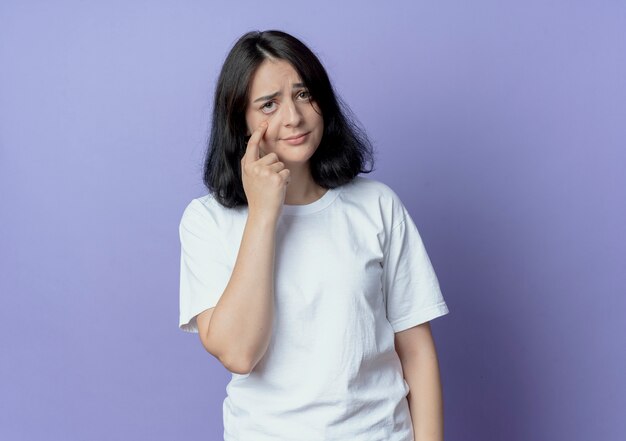 Unpleased young pretty caucasian girl wearing glasses pulling down eyelid isolated on purple background with copy space