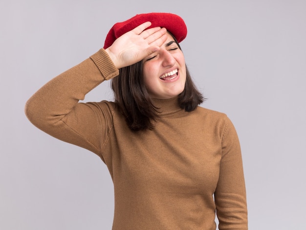 Unpleased young pretty caucasian girl with beret hat puts hand on forehead