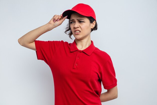 Unpleased young pretty delivery woman looking at side 