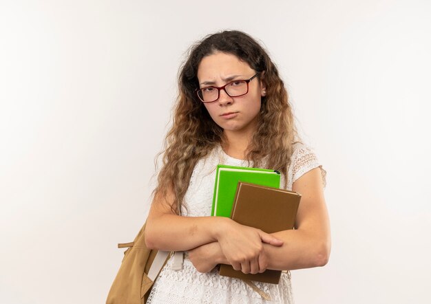 Unpleased young pretty schoolgirl wearing glasses and back bag holding books looking at camera isolated on white background with copy space