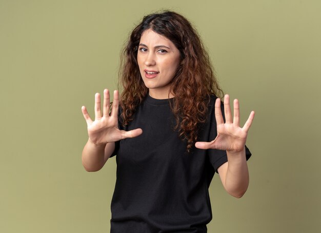 Unpleased young pretty woman looking at front doing stop gesture isolated on olive green wall with copy space